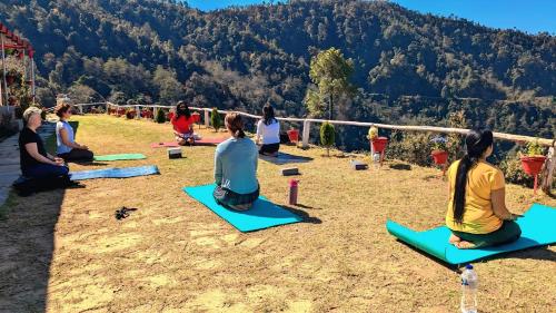 a group of people sitting in a yoga class in the mountains at Ghumakkad Stay in Jageshwar