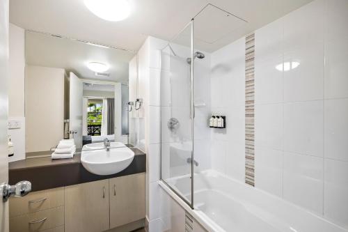 a white bathroom with a sink and a shower at 3 bedroom swim out apartment, right on the pool in Alexandra Headland , across from the beach in Alexandra Headland