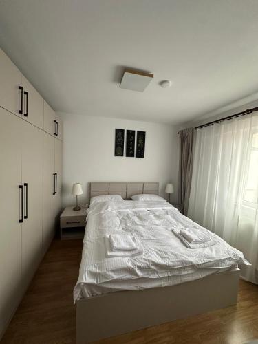 a white bedroom with a large bed and a window at Biverse Prestige in Petrila