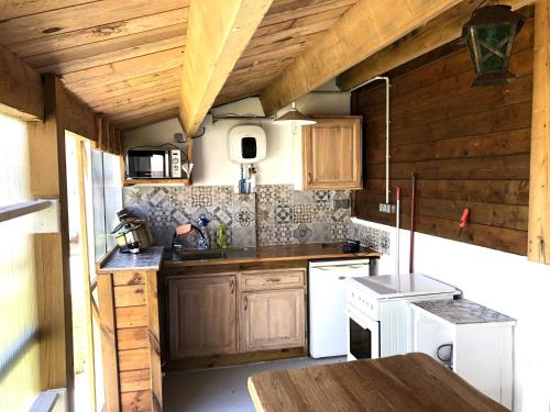 une cuisine avec des placards en bois et un appareil blanc dans l'établissement Gite Chambre Cuisine Parking à St Georges d'Oléron, à Saint-Georges-dʼOléron