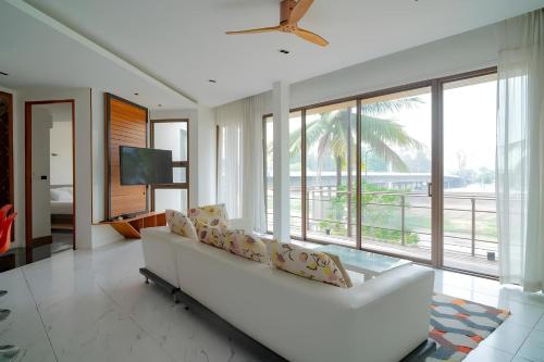 a living room with a white couch and a tv at Pool Villa Nam Nan in Nan