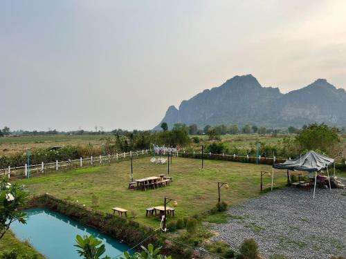 a picnic area with tables in a field with mountains at Idin Klin Pha Man in Ban Nong Pla Siu