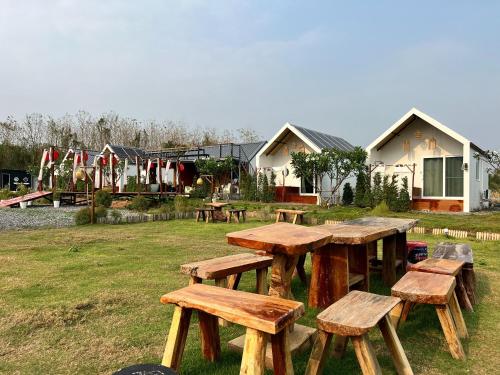 a group of wooden picnic tables in a field at Idin Klin Pha Man in Ban Nong Pla Siu