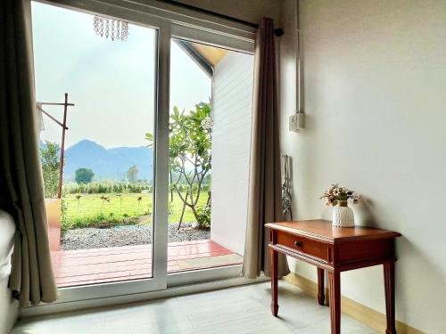 an open sliding glass door with a view of a field at Idin Klin Pha Man in Ban Nong Pla Siu