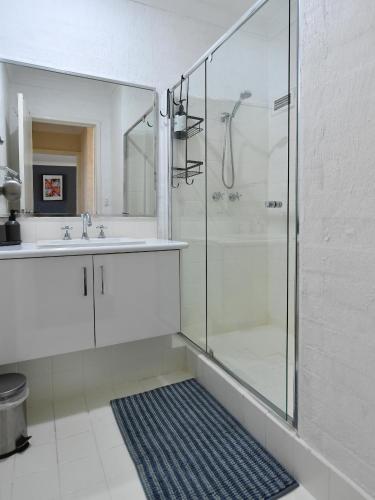 a bathroom with a glass shower and a sink at Surfside Sunset in Safety Bay