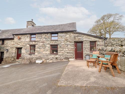 a stone house with a table and chairs in front of it at Y Bwthyn in Llanbedr