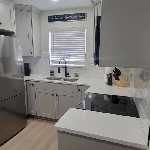 a white kitchen with a sink and a refrigerator at Cozy Cottage near USU in Logan