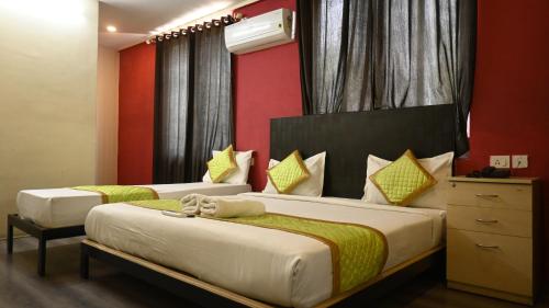 two beds in a room with red walls at Hotel Fusion Suites in Bangalore