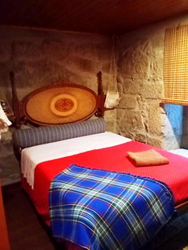 a bedroom with a bed with a red and blue blanket at Village Minhoure in Felgueiras