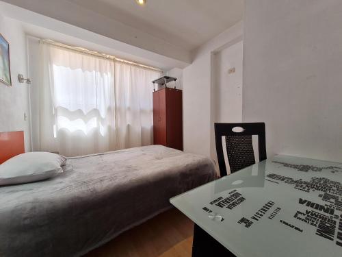 a bedroom with a bed and a table and a window at WASI in Cusco