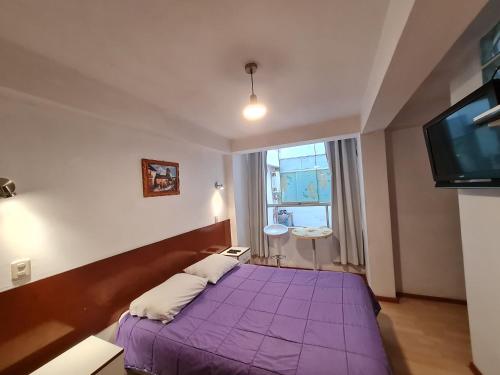 a bedroom with a purple bed and a window at WASI in Cusco