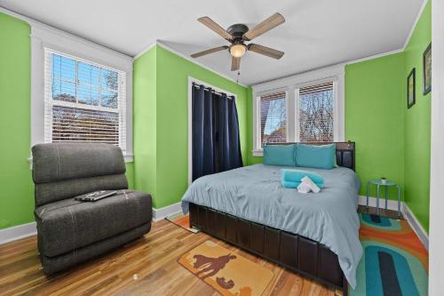 a bedroom with green walls and a bed and a chair at Cozy & Creative Top Unit in Lou's Arts District in Louisville