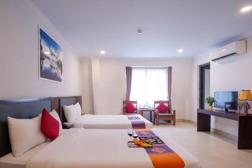サパにあるGrand Flamant Sapa Central Hotelのベッド2台と薄型テレビ付きのホテルの部屋
