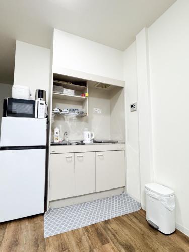 a kitchen with white cabinets and a refrigerator at Osaka Nimi family house direct KIX airport in Osaka
