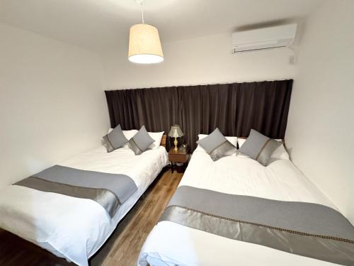 two beds sitting in a room with a window at Osaka Nimi family house direct KIX airport in Osaka
