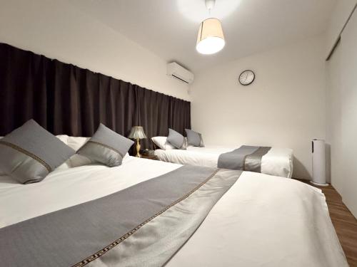 a bedroom with two beds and a clock on the wall at Osaka Nimi family house direct KIX airport in Osaka