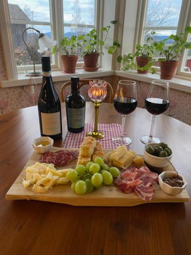 a cutting board with wine and cheese and wine glasses at Soltägtgården in Tällberg