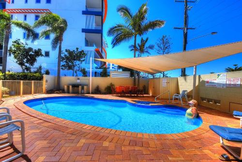 Una piscina con sombrilla y un edificio. en Bayview Beach Holiday Apartments, en Gold Coast