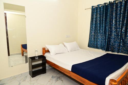 a bedroom with a bed with a blue curtain at George's Legacy Stay in Kāsarkod
