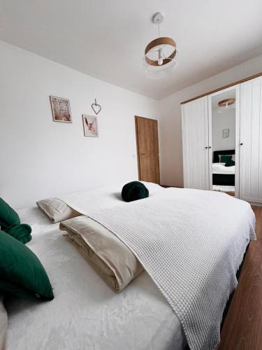 a bedroom with a large white bed with green pillows at Apartmány Hřensko in Hřensko
