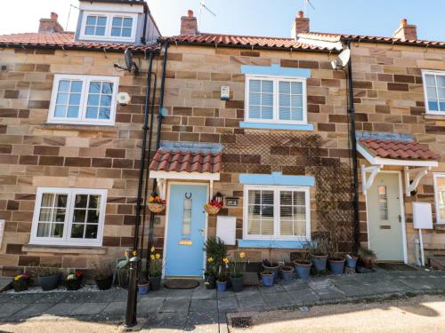 a brick house with blue doors and windows at Little Nest Cottage in Guisborough
