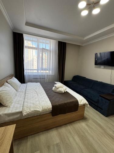 a bedroom with a bed and a flat screen tv at Уют студия in Astana