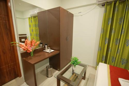 a bathroom with a vanity and a vase of flowers at Hotel Golden Residency in Mysore