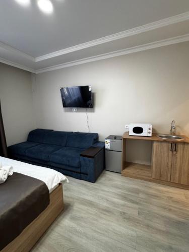 a bedroom with a bed and a couch and a tv at Уют студия in Astana