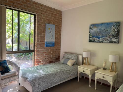 a bedroom with a bed and a brick wall at Mountain hideaway Blue Mountains in Kurrajong