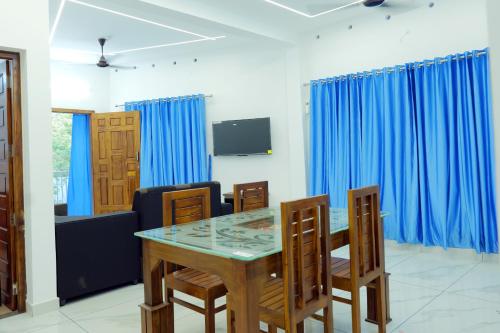 AlleppeySreeragam residency cherthala的一间设有蓝色窗帘和桌椅的用餐室