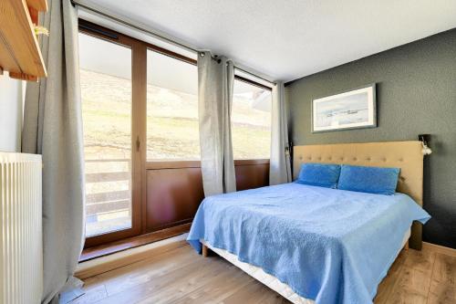 une chambre avec un lit bleu et une grande fenêtre dans l'établissement Résidence Le Montana - maeva Home - Appartement 2 pièces 6 personnes - Confort MAE-5501, à La Mongie