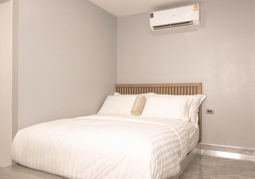 a bedroom with a white bed and a air conditioner at Cabanaz Pool Villa in Ban Zong Katiam