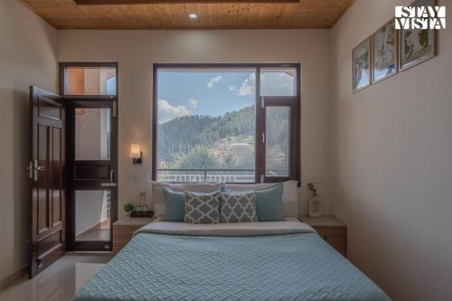 a bedroom with a bed with a large window at StayVista at Saraiya House with Bonfire & WiFi in Shimla