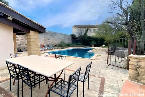 un patio avec une table et des chaises à côté d'une piscine dans l'établissement Le Mas de mon Père, à Vers-Pont-du-Gard