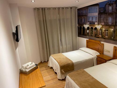 Una habitación de hotel con dos camas y un televisor. en Camiño Portugues, en Padrón