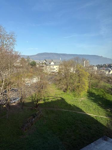 une vue sur un champ d'herbe avec des bâtiments en arrière-plan dans l'établissement Studio lumineux et élégant - parking gratuit, à Chambéry