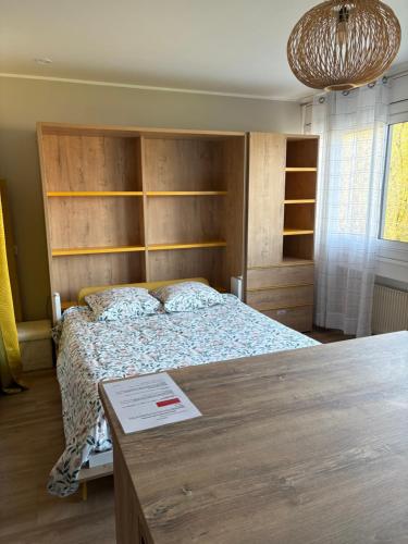 - une chambre avec un lit doté d'une tête de lit en bois et d'une table dans l'établissement Studio lumineux et élégant - parking gratuit, à Chambéry