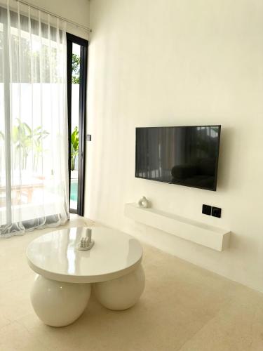 a white living room with a white table and a tv at The Ulu Hills in Uluwatu