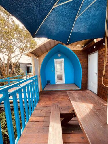 a blue porch with a wooden bench under a blue umbrella at 深山林內民宿 in Zhushan