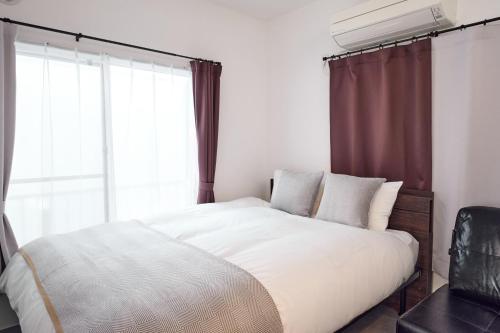 a bedroom with a white bed with a window at コートハウス三茶 in Tokyo