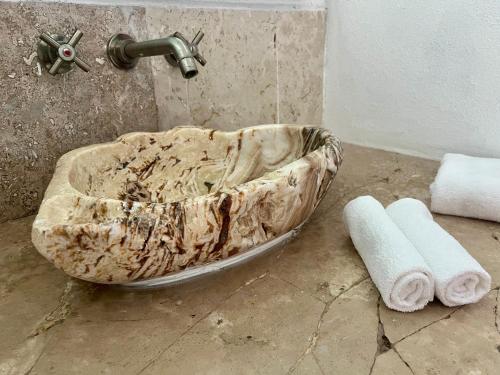 a stone sink in a bathroom with two rolled towels at Casa Paloma in Ixtapa
