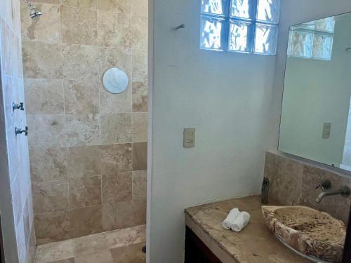 a bathroom with a sink and a shower with a mirror at Casa Paloma in Ixtapa