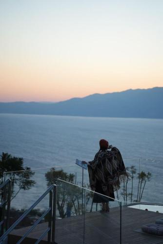 a person standing on a deck looking at the ocean at Fuxian Lake Three Thousand French Manor Hotel in Xujiadu