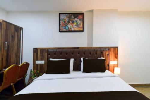 a bedroom with a large bed with a wooden headboard at Super Townhouse Vanasthalipuram Formerly Hotel Surabhi in Hyderabad