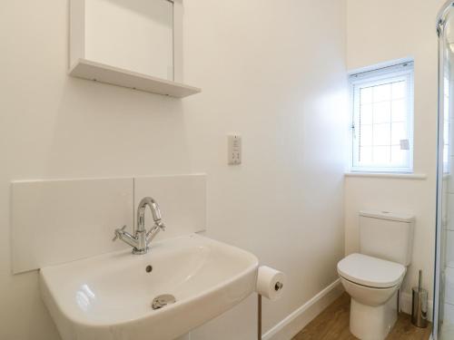 a white bathroom with a sink and a toilet at Little Danns in Hailsham