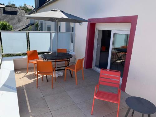 a patio with a table and chairs and an umbrella at Le Mandarine, T2 proche plage de Morgat in Crozon