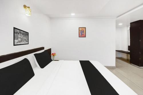 a black and white bed in a white room at Super Townhouse City Center Near Mysore Palace Formerly Aavass Inn in Mysore