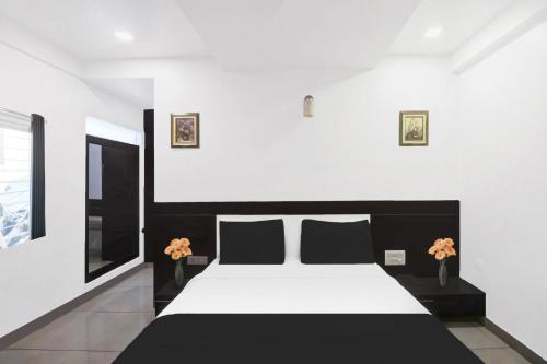 a bedroom with a black and white bed with flowers at Super Townhouse City Center Near Mysore Palace Formerly Aavass Inn in Mysore