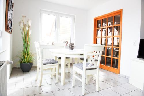 a white dining room with a white table and chairs at Passat in Norddeich
