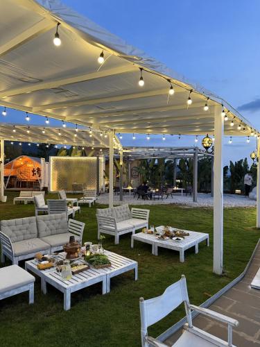 a patio with couches and tables under a tent at Fuxian Lake Three Thousand French Manor Hotel in Xujiadu